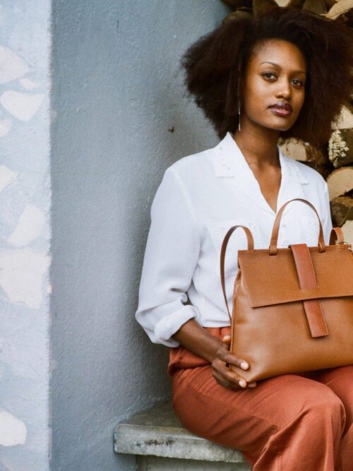 Elegantly styled bag. Quality caramel-colored leather. with handle and adjustable shoulder strap. holds a book, iPad, water bottle. handmade in Geneva with eco-responsible leathers.