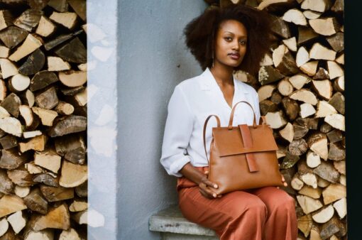 Elegantly styled bag. Quality caramel-colored leather. with handle and adjustable shoulder strap. holds a book, iPad, water bottle. handmade in Geneva with eco-responsible leathers.